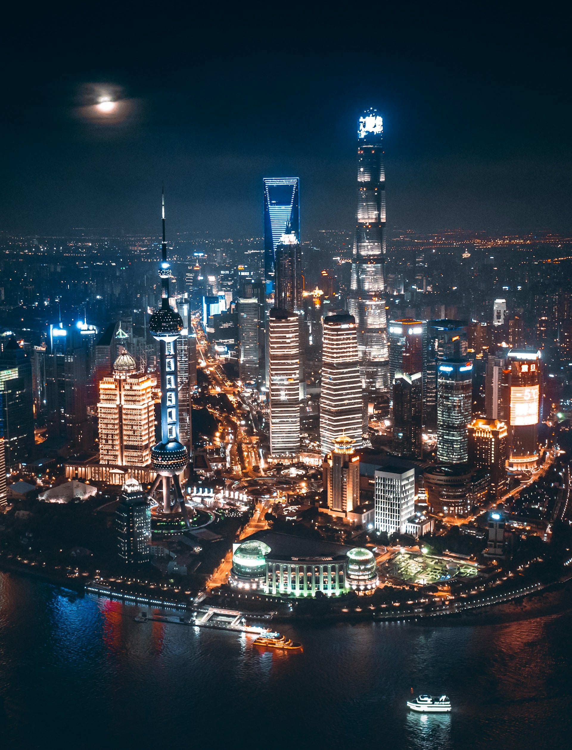 Night view of Shanghai's skyline featuring the Oriental Pearl Tower, Shanghai Tower, Shanghai World Financial Center, and Jin Mao Tower beside the Huangpu River.